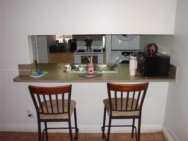 kitchen featuring tile patterned floors, sink, stacked washing maching and dryer, and white stove