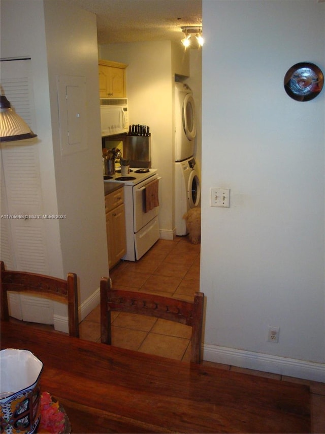 kitchen with light tile patterned flooring, white appliances, and stacked washer and dryer