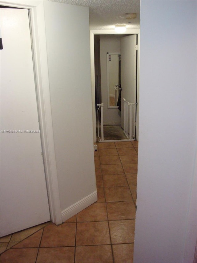 hallway with tile patterned flooring and a textured ceiling