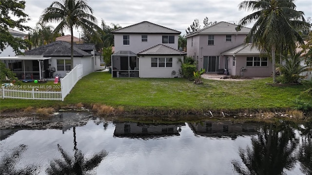 rear view of property with a sunroom, a yard, and a water view