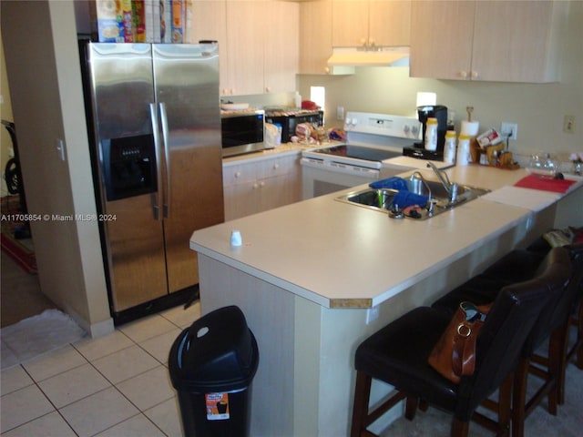 kitchen featuring a kitchen bar, kitchen peninsula, stainless steel appliances, sink, and light brown cabinets