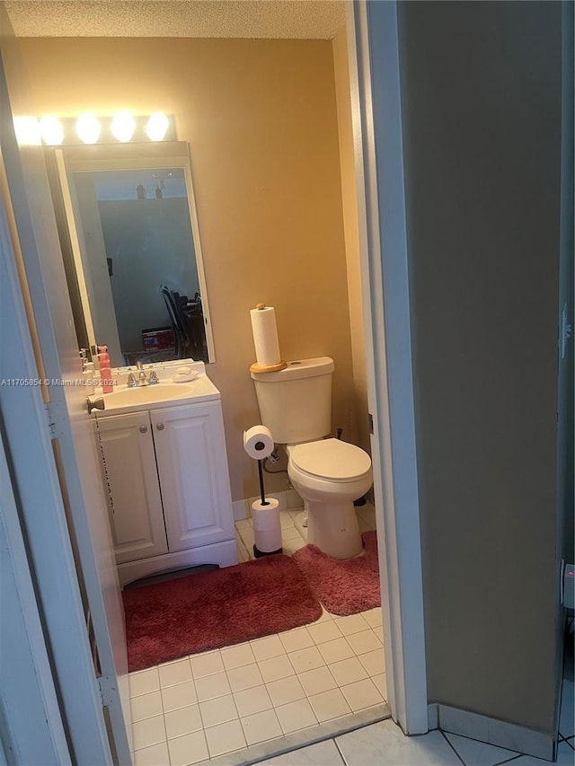 bathroom with tile patterned flooring, vanity, toilet, and a textured ceiling