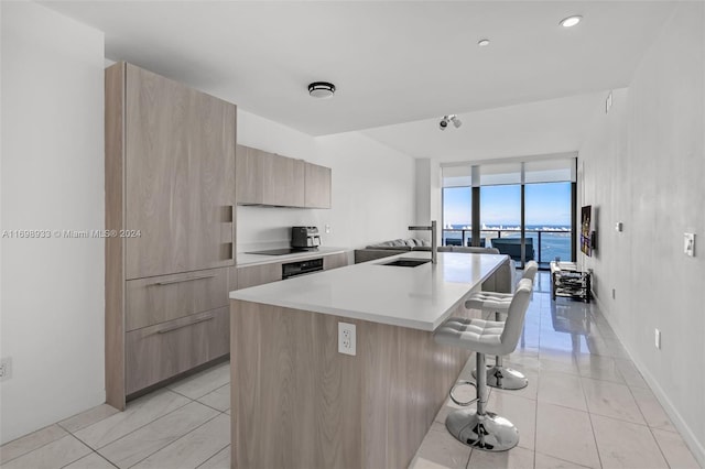 kitchen featuring sink, a breakfast bar area, a center island with sink, a water view, and black appliances