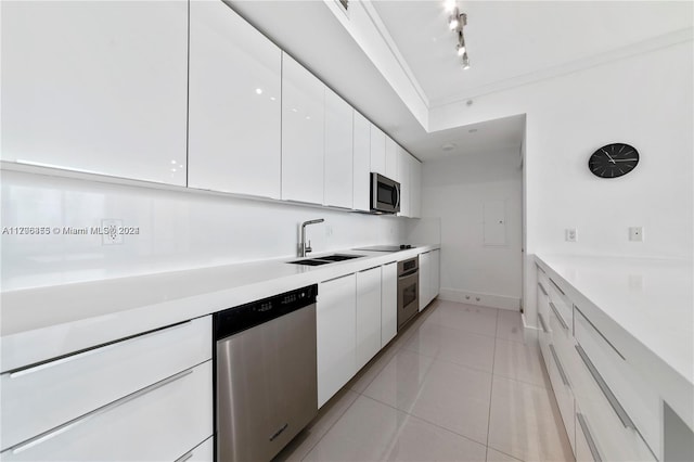 kitchen with track lighting, white cabinets, sink, light tile patterned floors, and stainless steel appliances