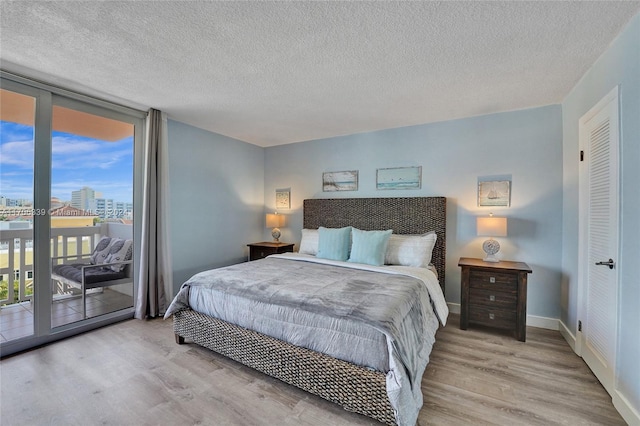 bedroom featuring access to exterior, a textured ceiling, and light hardwood / wood-style flooring