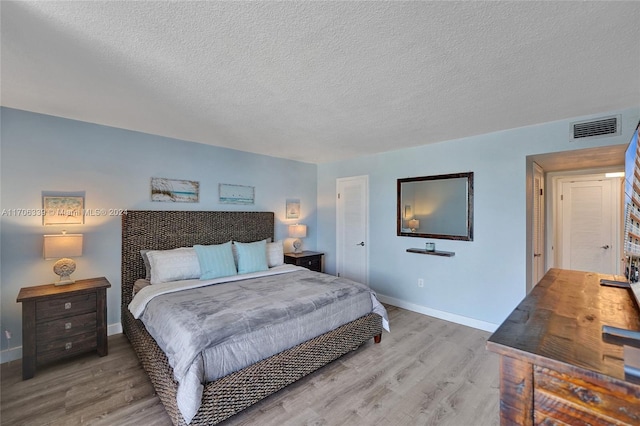 bedroom with a textured ceiling and light hardwood / wood-style flooring