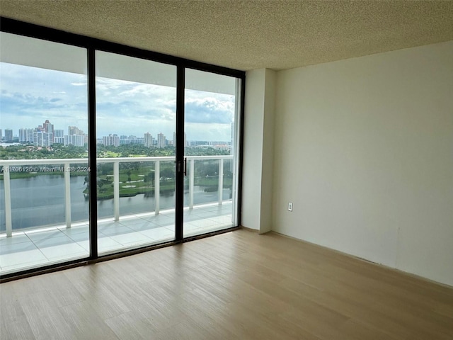 spare room with light hardwood / wood-style floors, a water view, and floor to ceiling windows