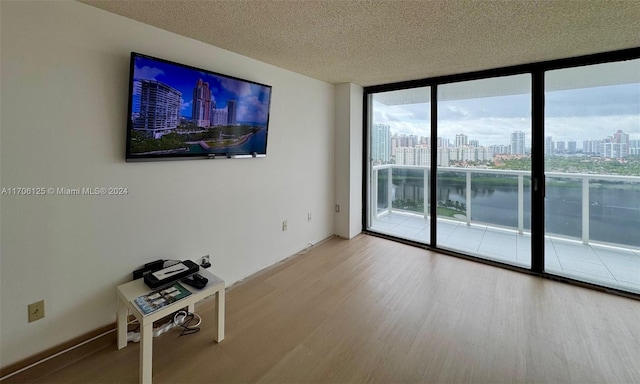 spare room featuring hardwood / wood-style flooring, a wall of windows, and a textured ceiling