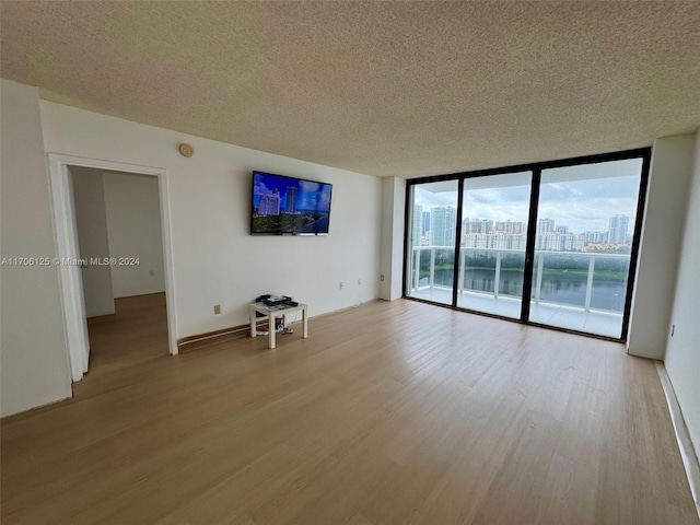 unfurnished living room with a textured ceiling, light hardwood / wood-style floors, and floor to ceiling windows