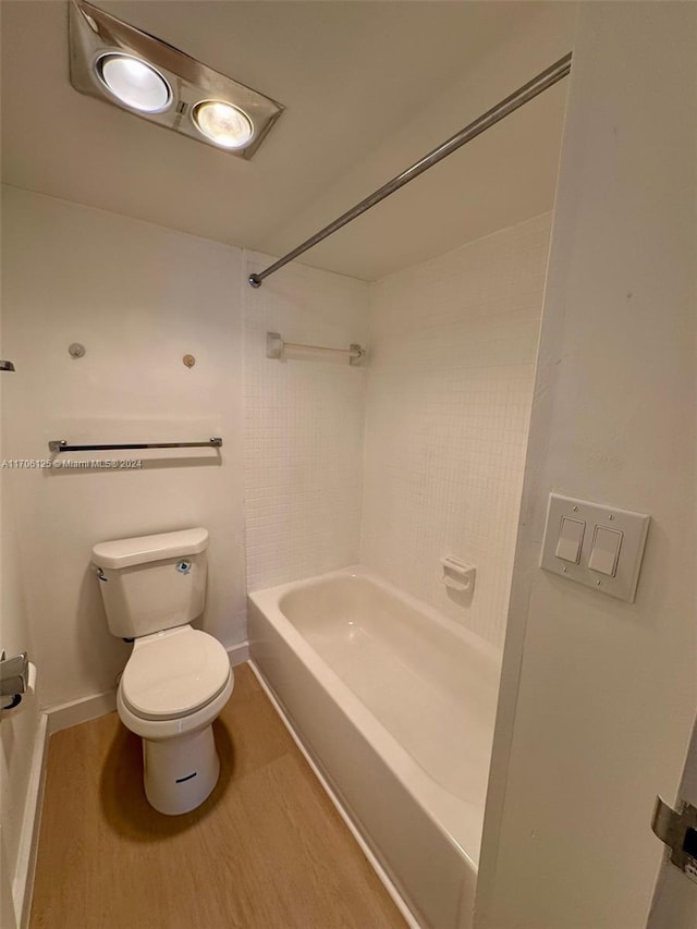 bathroom with hardwood / wood-style flooring, toilet, and bathing tub / shower combination