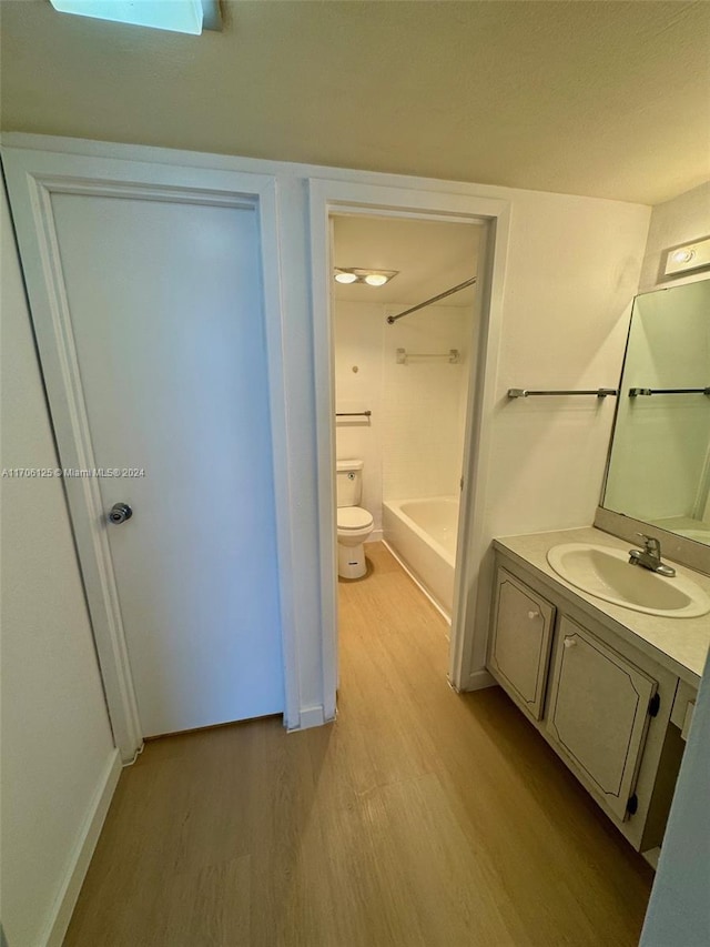 bathroom featuring vanity, toilet, wood-type flooring, and a tub