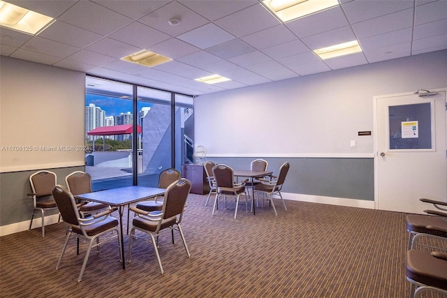 carpeted dining area featuring a drop ceiling