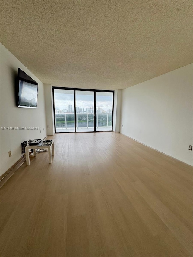 unfurnished living room with hardwood / wood-style floors, expansive windows, and a textured ceiling