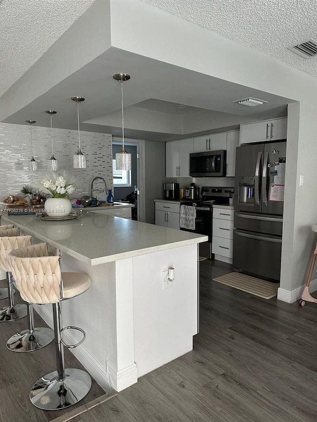 kitchen with stainless steel appliances, tasteful backsplash, pendant lighting, a kitchen bar, and white cabinets