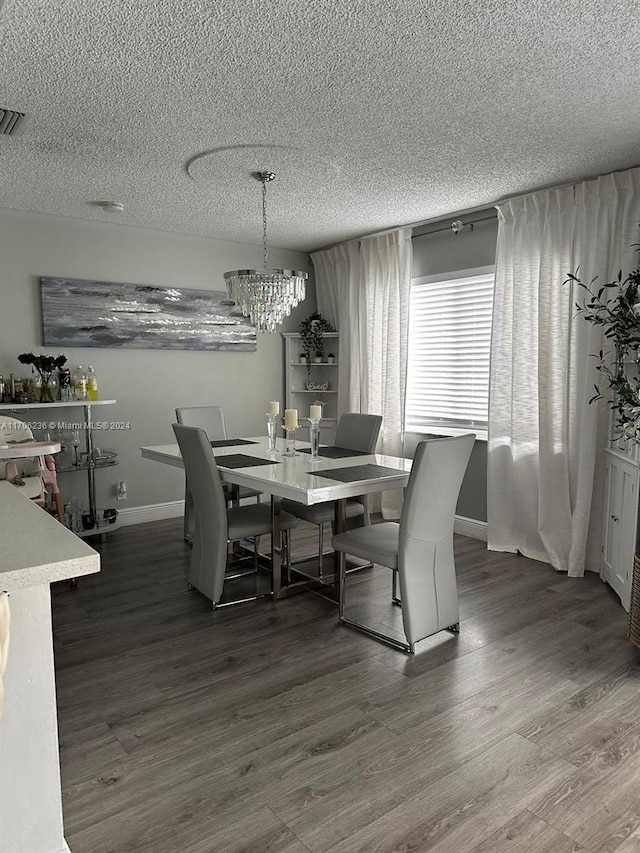 dining space with hardwood / wood-style floors, a textured ceiling, and an inviting chandelier