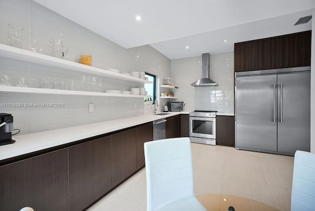 kitchen with sink, wall chimney exhaust hood, stainless steel appliances, tasteful backsplash, and light tile patterned floors