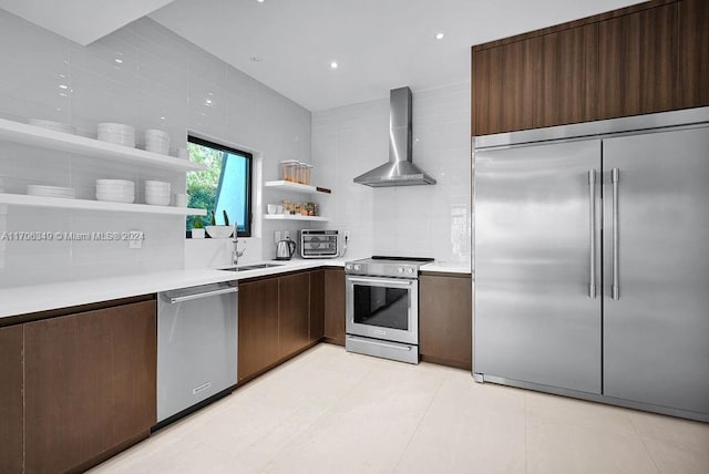 kitchen featuring decorative backsplash, stainless steel appliances, sink, wall chimney range hood, and light tile patterned flooring