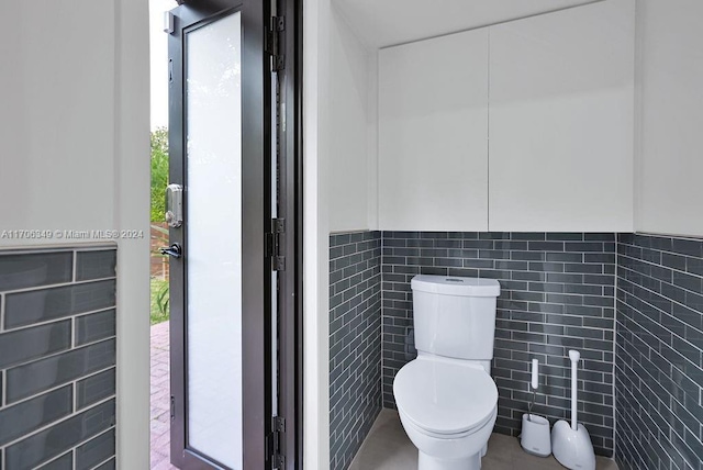 bathroom featuring toilet and tile walls