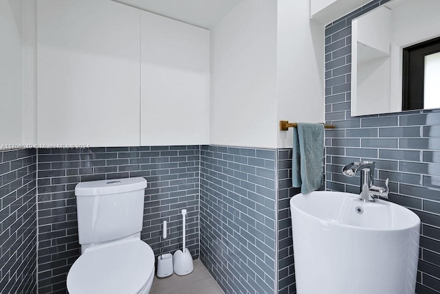 bathroom featuring toilet and tile walls