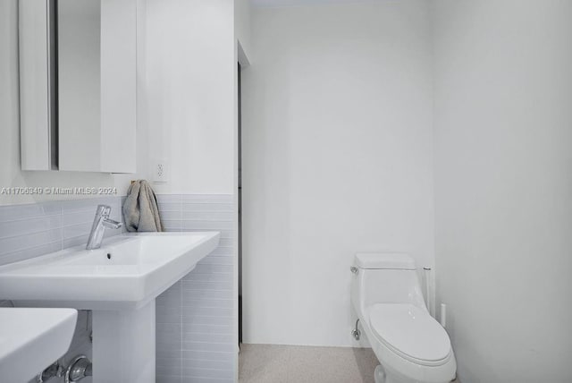 bathroom featuring sink, toilet, and tile walls