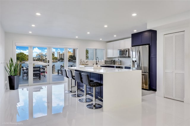 kitchen with a breakfast bar, white cabinetry, a center island, light tile patterned floors, and stainless steel appliances