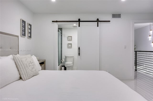 bedroom featuring a barn door and ensuite bath