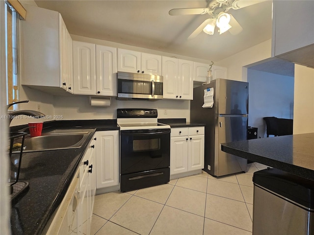 kitchen with light tile patterned floors, appliances with stainless steel finishes, white cabinetry, a sink, and ceiling fan