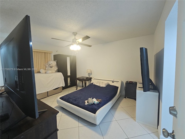 tiled bedroom with ceiling fan and a textured ceiling