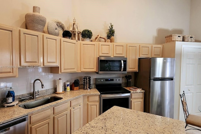 kitchen with light stone countertops, appliances with stainless steel finishes, and sink