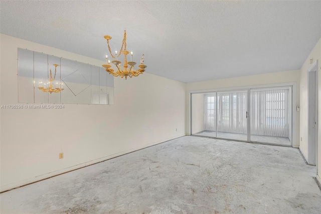 spare room with a textured ceiling and an inviting chandelier