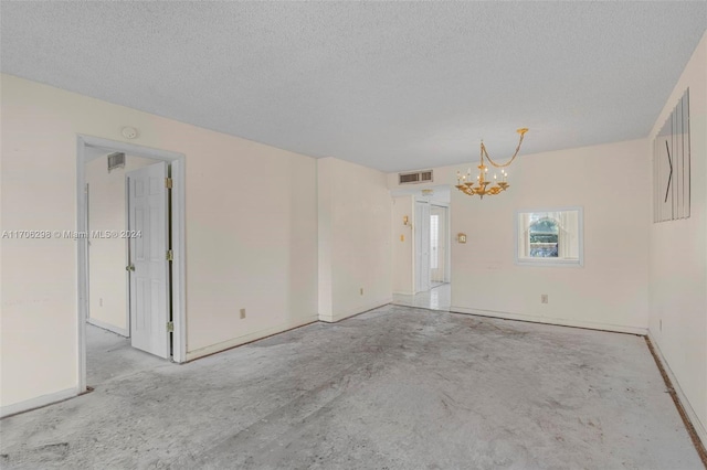 spare room with a textured ceiling and a chandelier