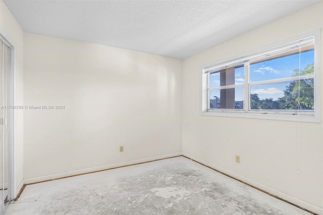 spare room with a textured ceiling and concrete floors