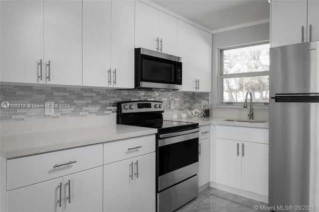 kitchen featuring white cabinets, appliances with stainless steel finishes, decorative backsplash, and sink