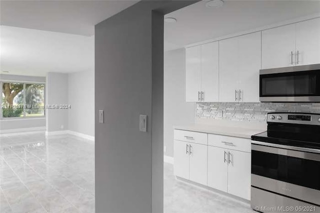 kitchen featuring stainless steel appliances, white cabinets, and tasteful backsplash