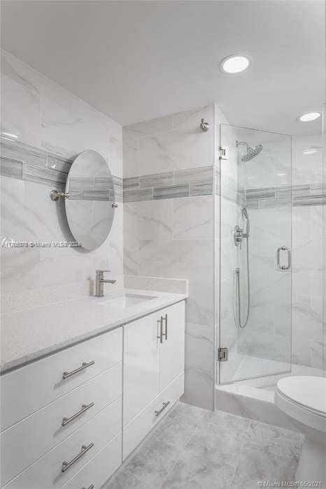 bathroom featuring a shower with door, vanity, and toilet