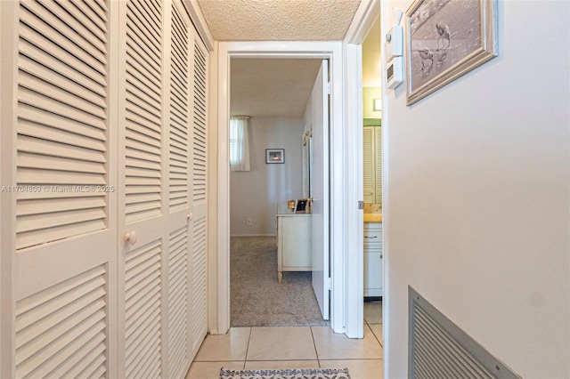 hallway with light tile patterned floors and a textured ceiling