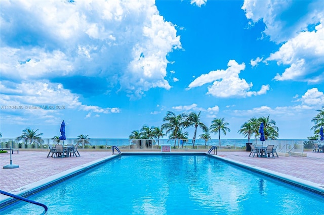 view of swimming pool featuring a water view and a patio area