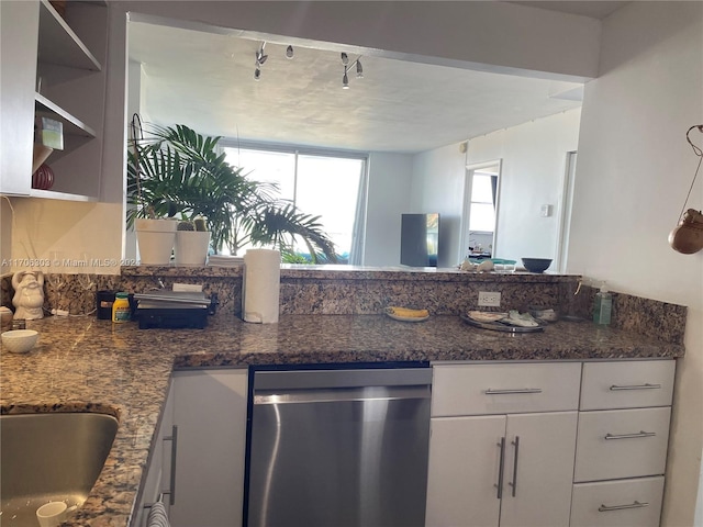 kitchen featuring dishwasher, rail lighting, white cabinetry, and dark stone counters