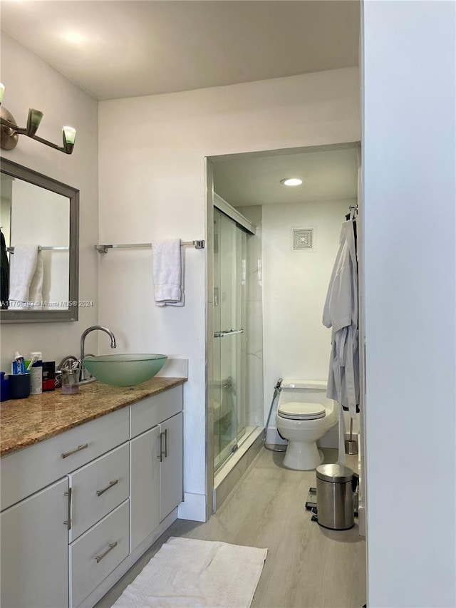 bathroom featuring toilet, vanity, an enclosed shower, and hardwood / wood-style flooring