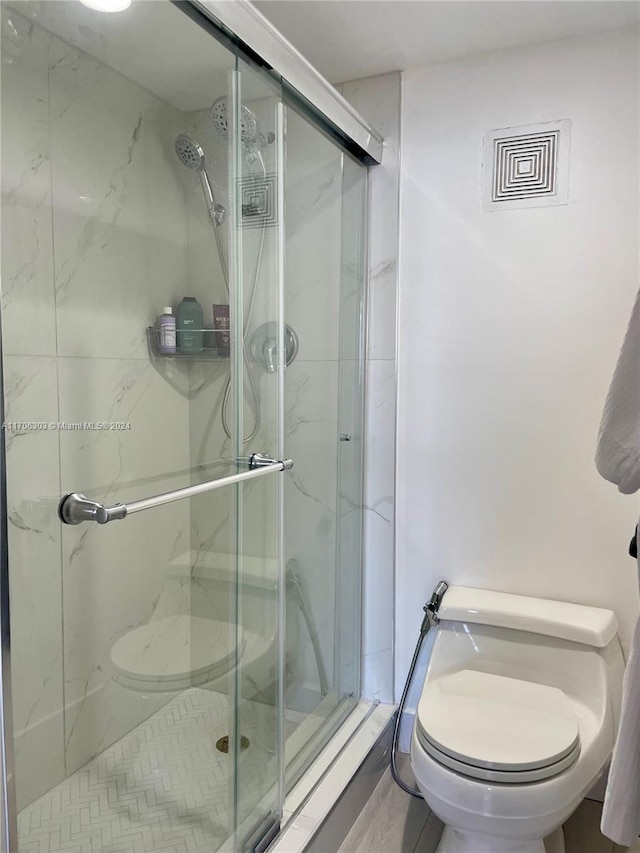 bathroom featuring toilet and a shower with door