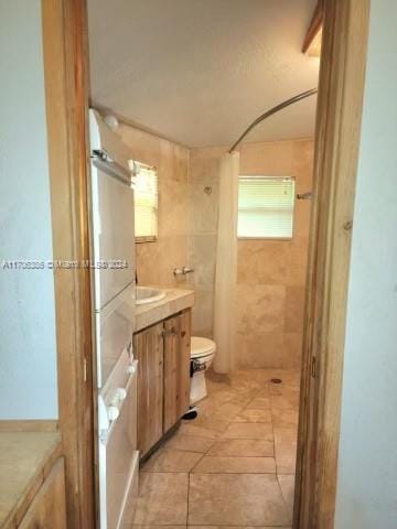 bathroom featuring a shower, vanity, tile patterned floors, and toilet