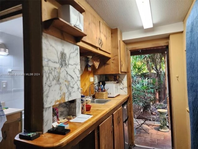 kitchen featuring tasteful backsplash, sink, and a textured ceiling