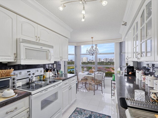 kitchen with an inviting chandelier, light tile patterned floors, white appliances, a textured ceiling, and white cabinets