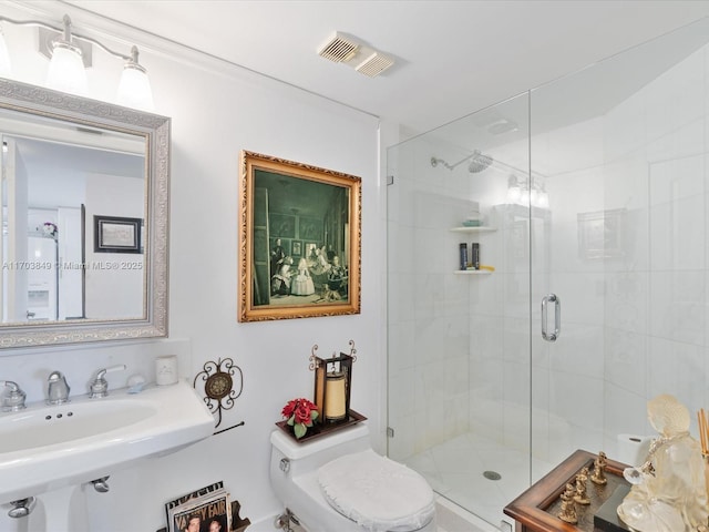 bathroom featuring toilet, a shower with door, and sink