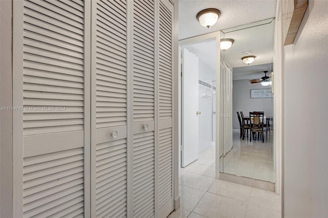 hall featuring light tile patterned floors and a textured ceiling