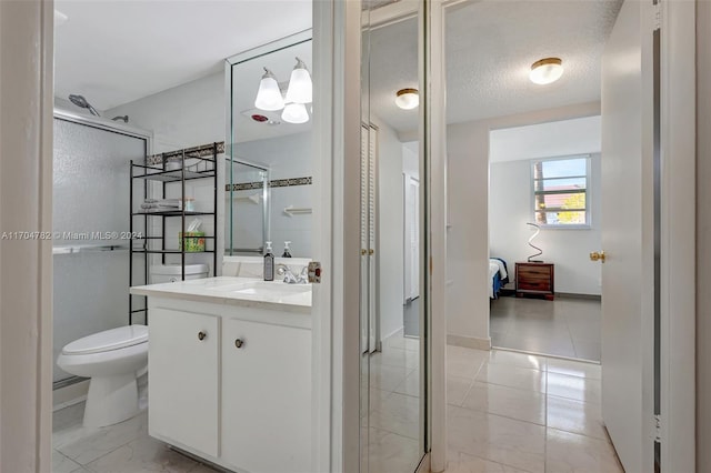 bathroom with a shower with door, vanity, a textured ceiling, and toilet