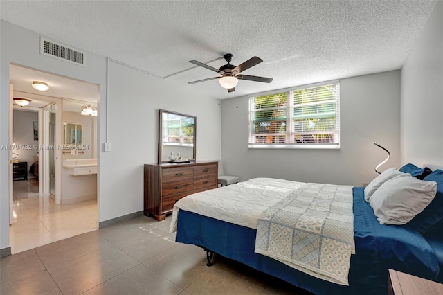 bedroom with connected bathroom, ceiling fan, tile patterned flooring, and a textured ceiling