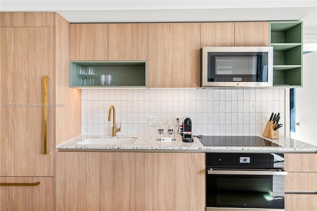 kitchen with sink, wall oven, light stone counters, black electric cooktop, and decorative backsplash