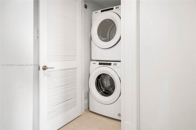 laundry room featuring light tile patterned flooring and stacked washer / dryer