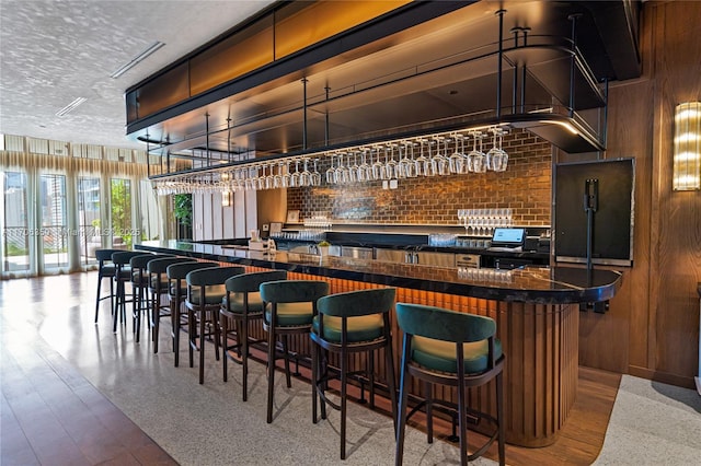 bar with a textured ceiling and wood walls